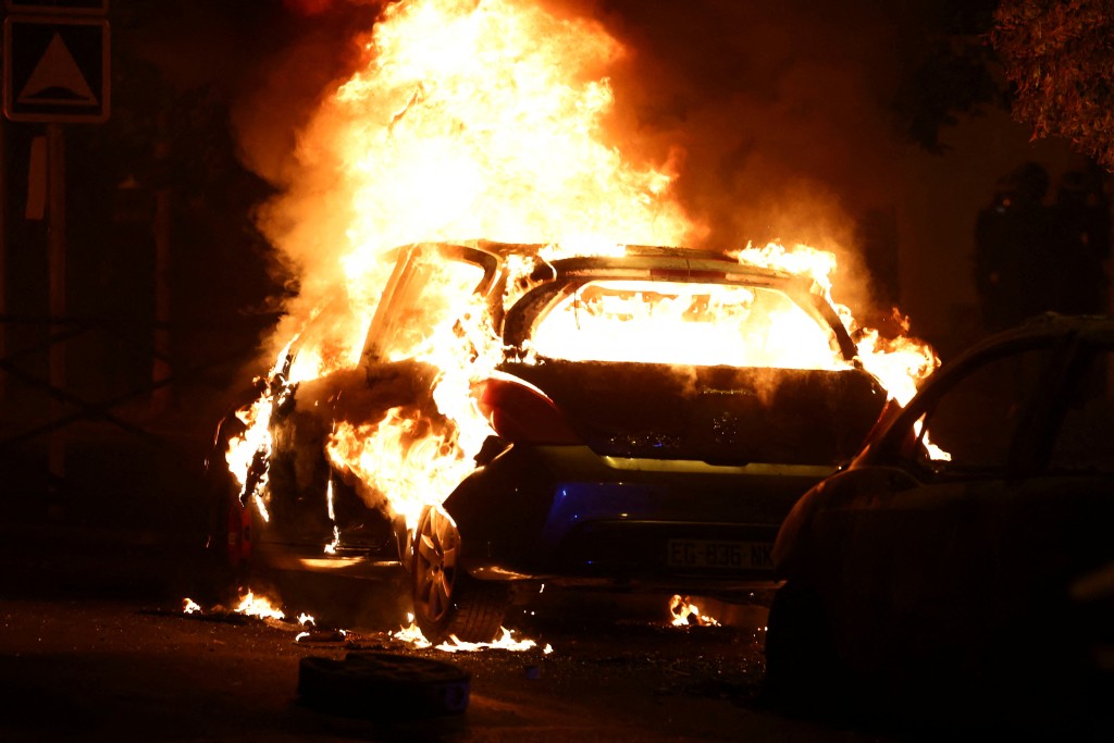 骚扰中，示威者与警察发生冲突，一辆汽车被烧毁。路透社