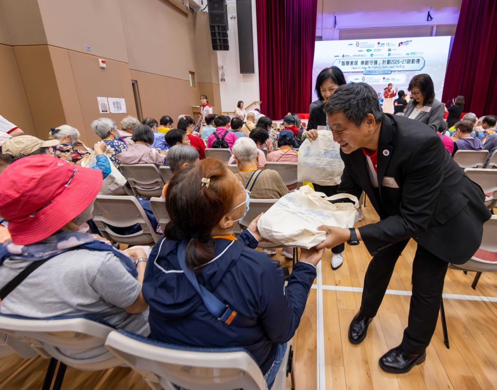 電能實業行政總裁蔡肇中與義工向參與啟動禮的長者派發福袋。