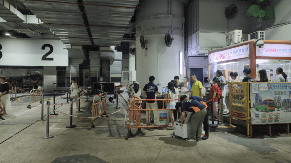 總站內可見多輛跨境旅遊巴停泊候命，職員在櫃位為旅客辦理購票及登車安排。黎志偉攝