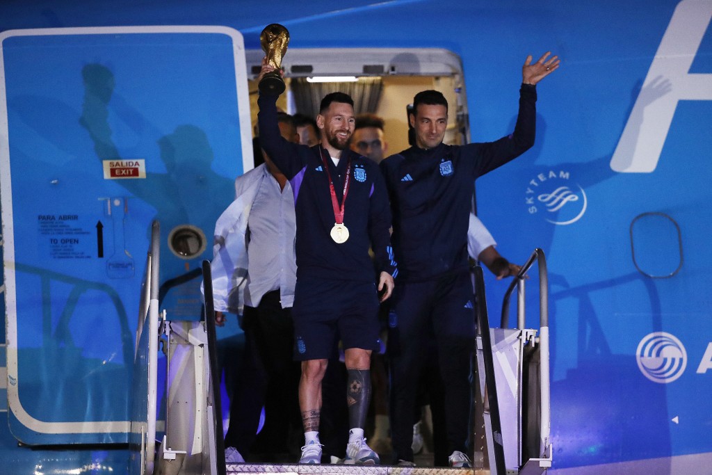 美斯(左)举起世界杯步出机舱。Reuters