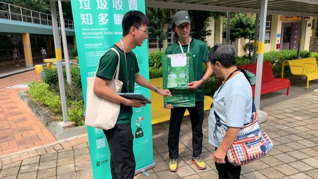 「綠展隊」向一名觀塘區居民介紹垃圾收費的資料。政府新聞處
