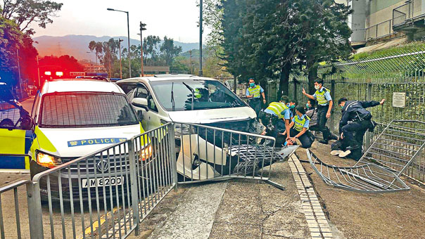 ■警車將被搶的七人車夾至剷上行人路撞欄停下,警員在車旁制服疑匪。