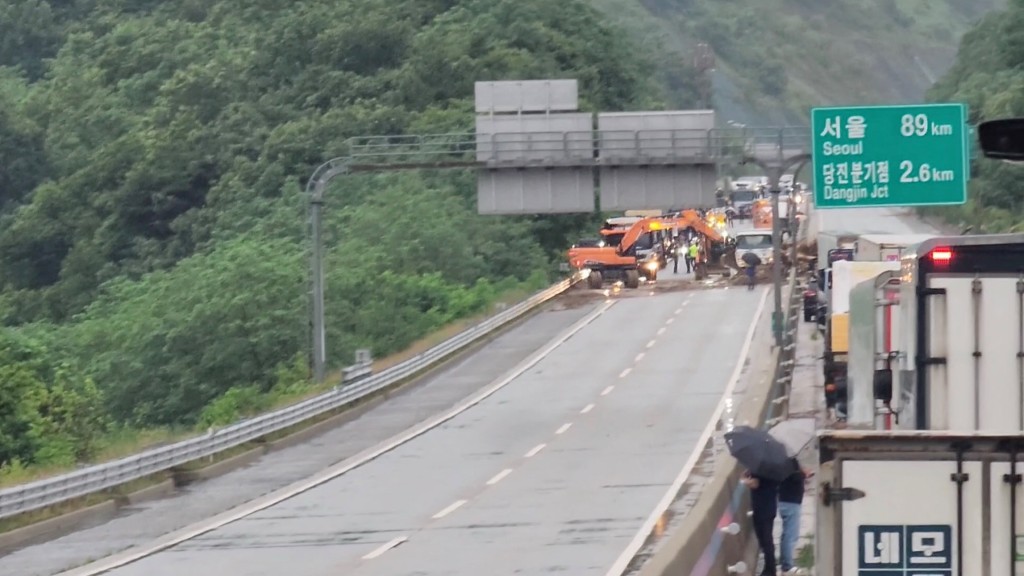 南韓暴雨過後,救援人員在唐津市用挖土機清理山泥傾瀉滑下的樹枝和泥土。 路透社 南韓暴雨過後,救援人員在唐津市用挖土機清理山泥傾瀉滑下的樹枝和泥土。 路透社