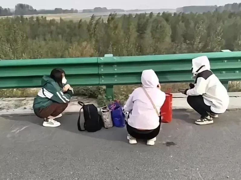 走累的富士康員工蹲在高速公路路邊休息。