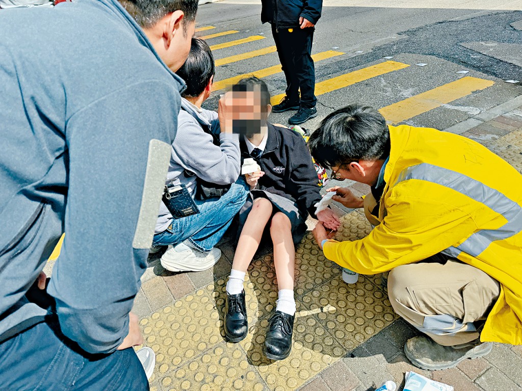 途人上前救助一名倒地的女學生。