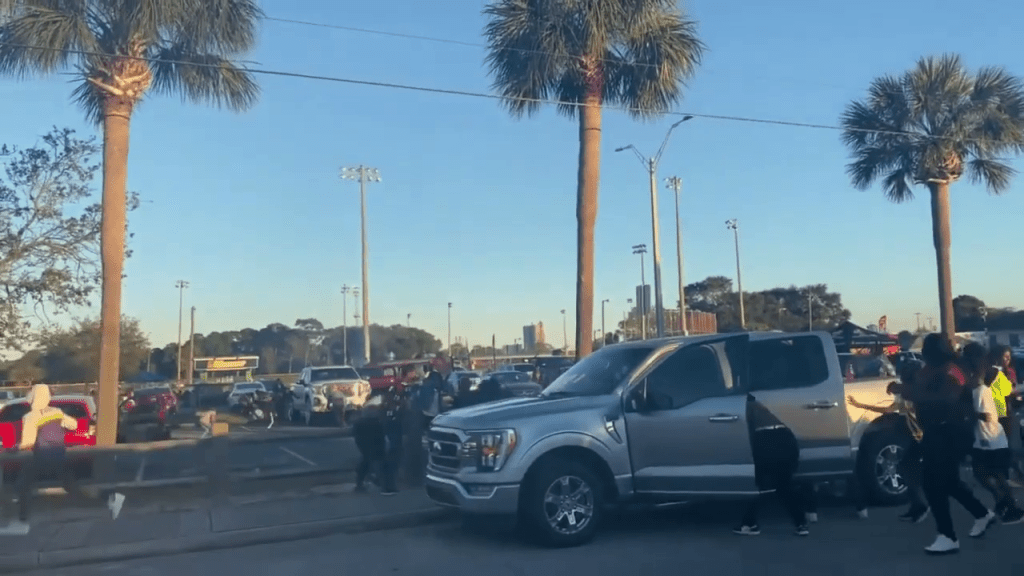 在佛羅里達州皮爾斯堡市，現場傳出槍聲，途人躲在汽車後面。網片截圖