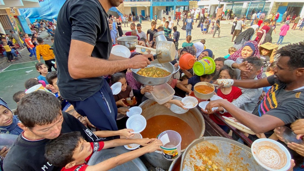 許多加沙人在聯合國營運的學校避難，圖為身在拉法的難民排隊領取食物。 路透社