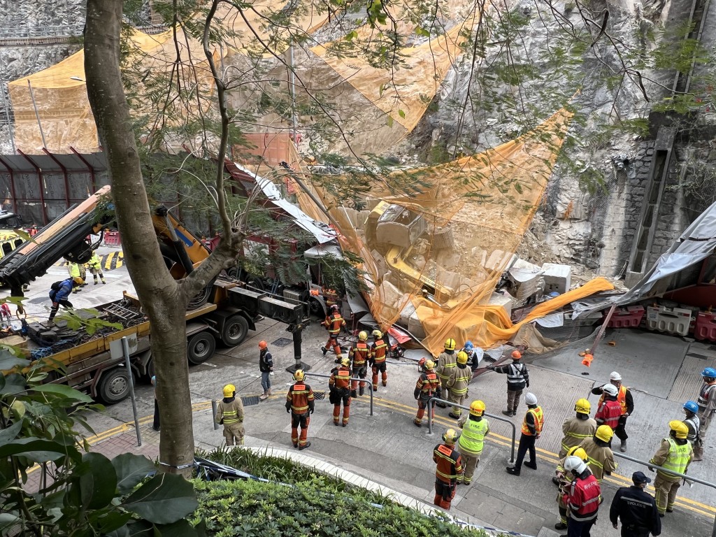 垃圾車被倒塌圍板壓住車頭。