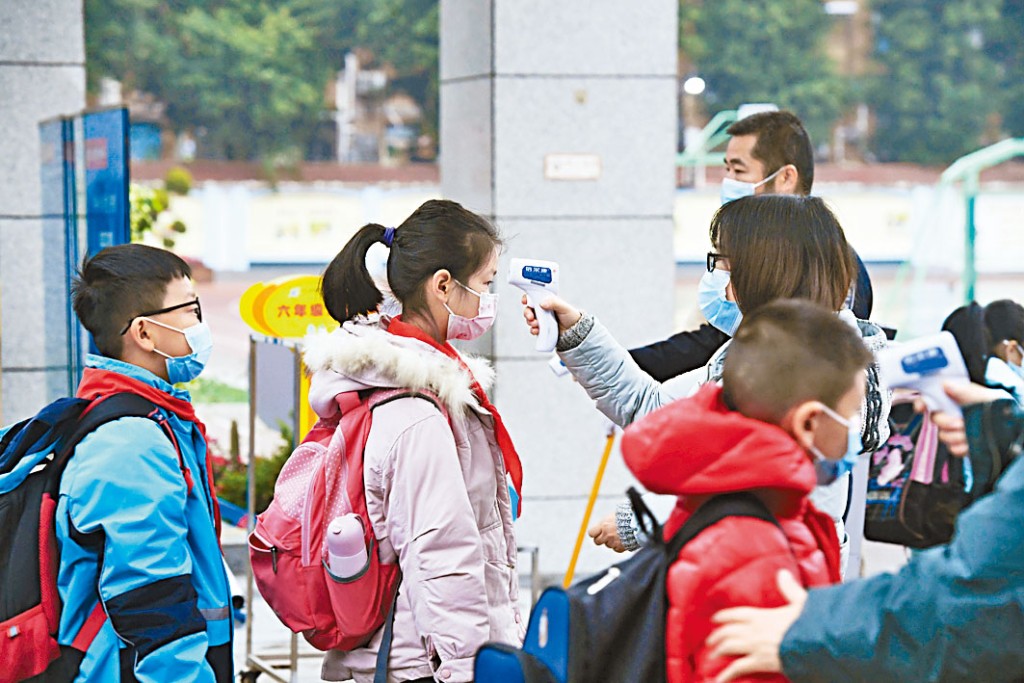重慶一小學學生戴口罩,測溫進入校園。