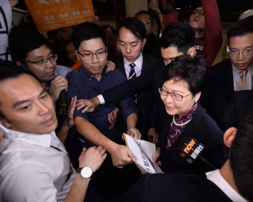 林郑在重重保护下落车，接过请愿信后步入酒店会场。