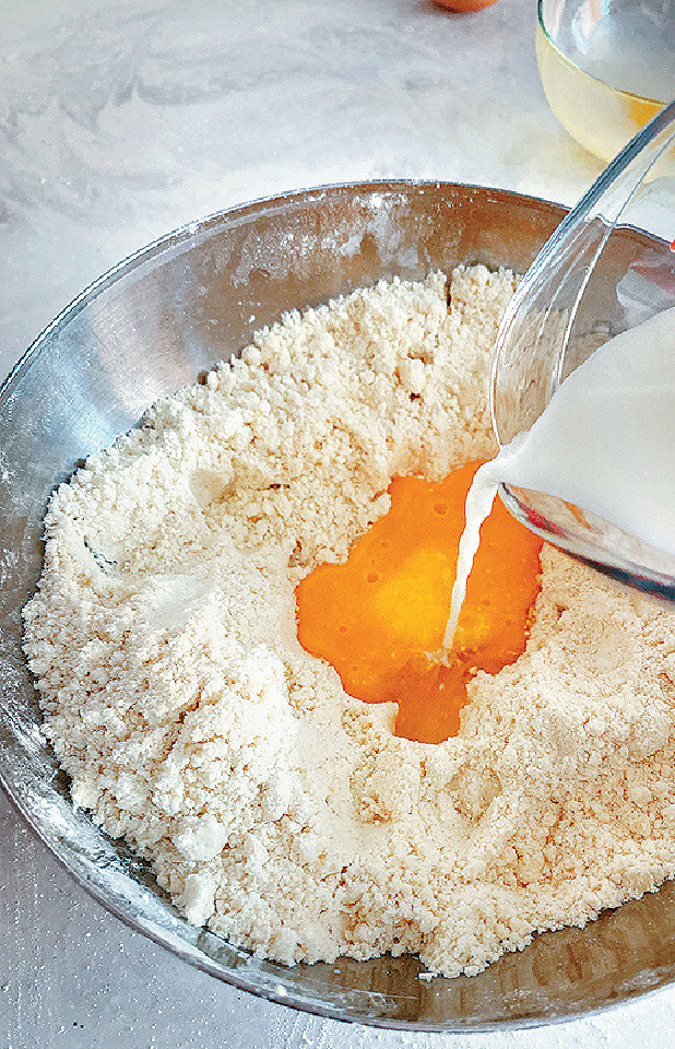 注入雞蛋漿、暖牛奶和檸檬汁，用刀背拌勻。