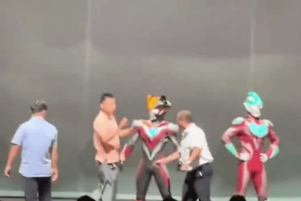 一名穿粉色恤衫的大叔上舞台衝向一名「鹹蛋超人」。