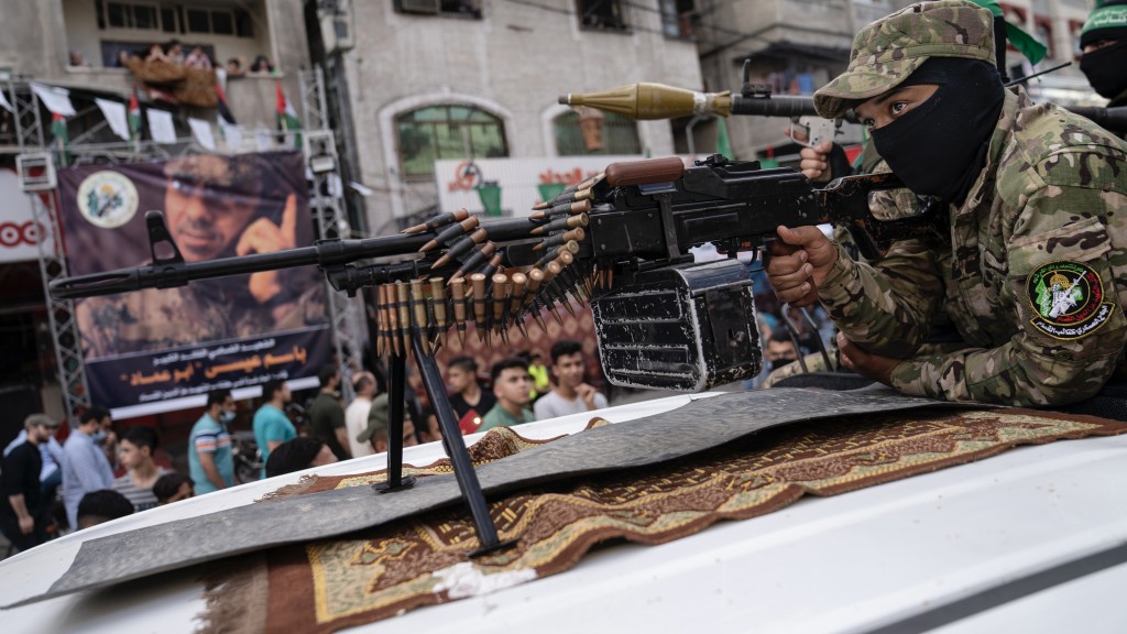 一名哈马斯武装分子在卡车顶上举着小队自动武器，为阵亡高级指挥官伊萨（Bassem Issa）游行。 美联社