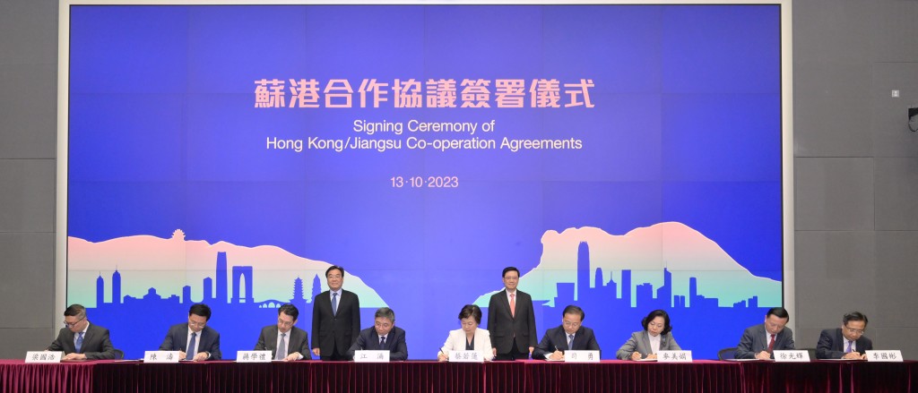 李家超（后排右）与信长星（后排左）见证两地政府部门和机构签署五份合作文件。