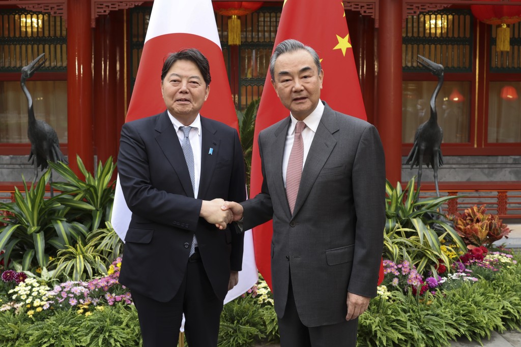 中央外事办主任王毅，与到访的日本外相林芳正握手。AP