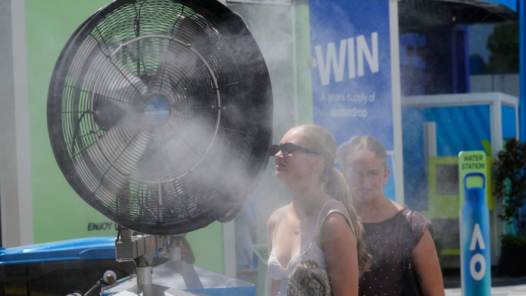 澳洲女子直接走到噴水的風扇前降溫。 美聯社