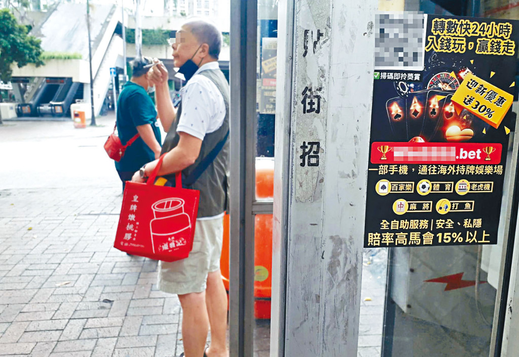 非法賭博集團派員到大埔廣場賽馬會投注站附近電話亭張貼宣傳單張，拉攏賭客參與非法賭博。李建人攝