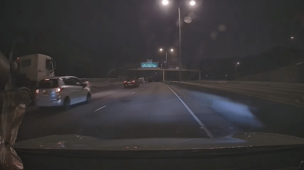 隨即「擺尾」反彈，如「打波子」般橫跨全部三條行車線，猛烈撞向左邊路壆，現場揚起大量沙塵。