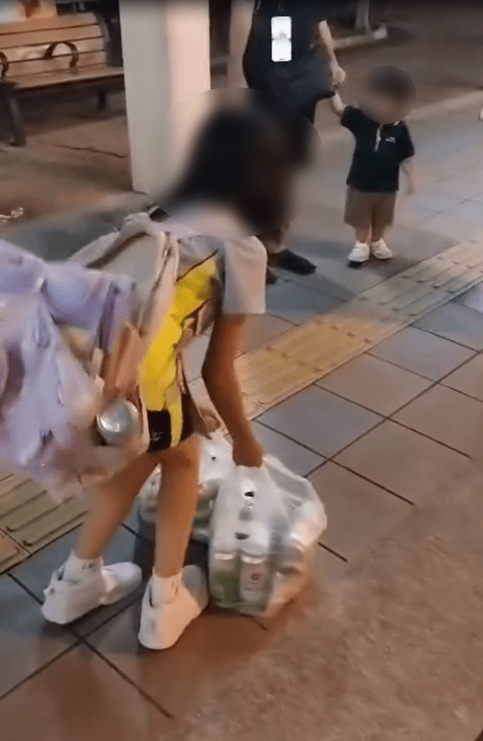 由於重量超出負荷,女童不時要放下膠袋稍為小休,亦跟不上父親步伐。(Threads影片截圖) 由於重量超出負荷,女童不時要放下膠袋稍為小休,亦跟不上父親步伐。(Threads影片截圖)