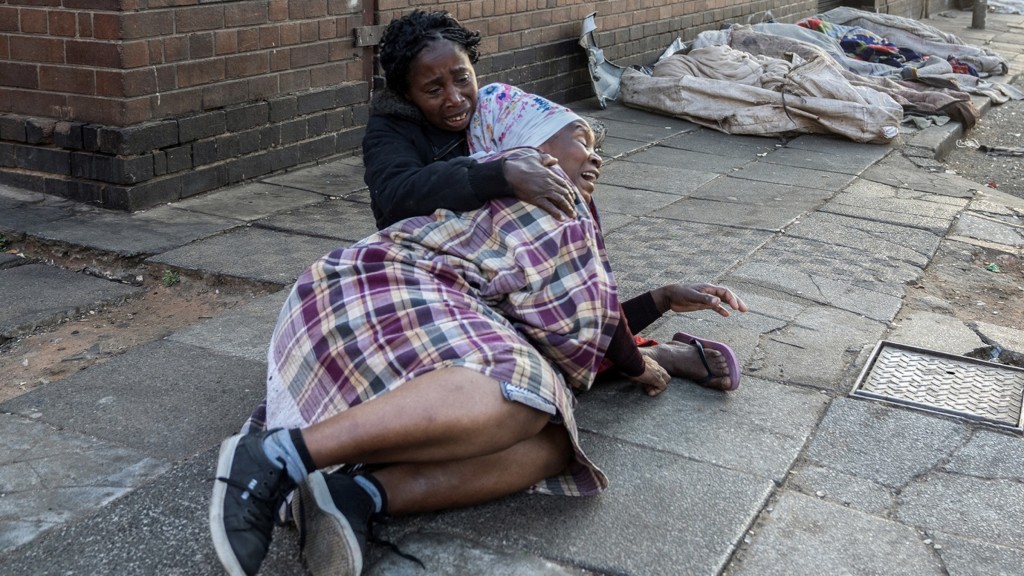 南非約翰內斯堡建築物大火，民眾在附近倒地痛哭。 路透社