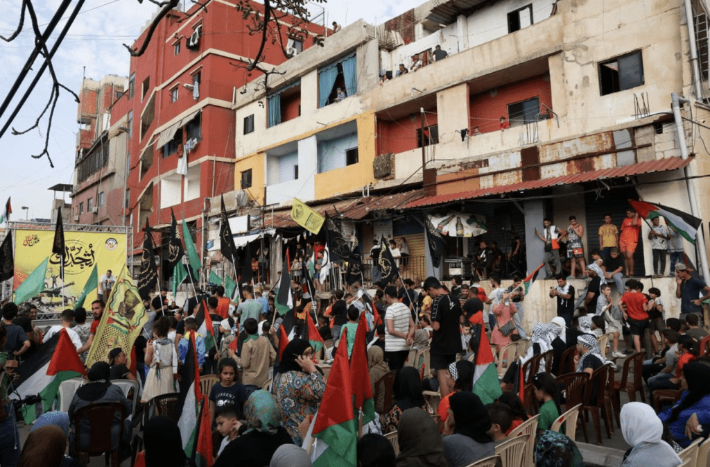 2023 年 10 月 11 日，黎巴嫩贝鲁特难民营，巴勒斯坦难民在集会期间举著旗帜，表达对加萨巴勒斯坦人的声援。路透社
