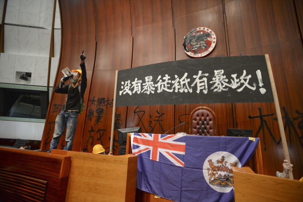 示威者在會議廳內拉起寫上「沒有暴徒 袛有暴政」黑色橫額及展示港英旗幟。資料圖片