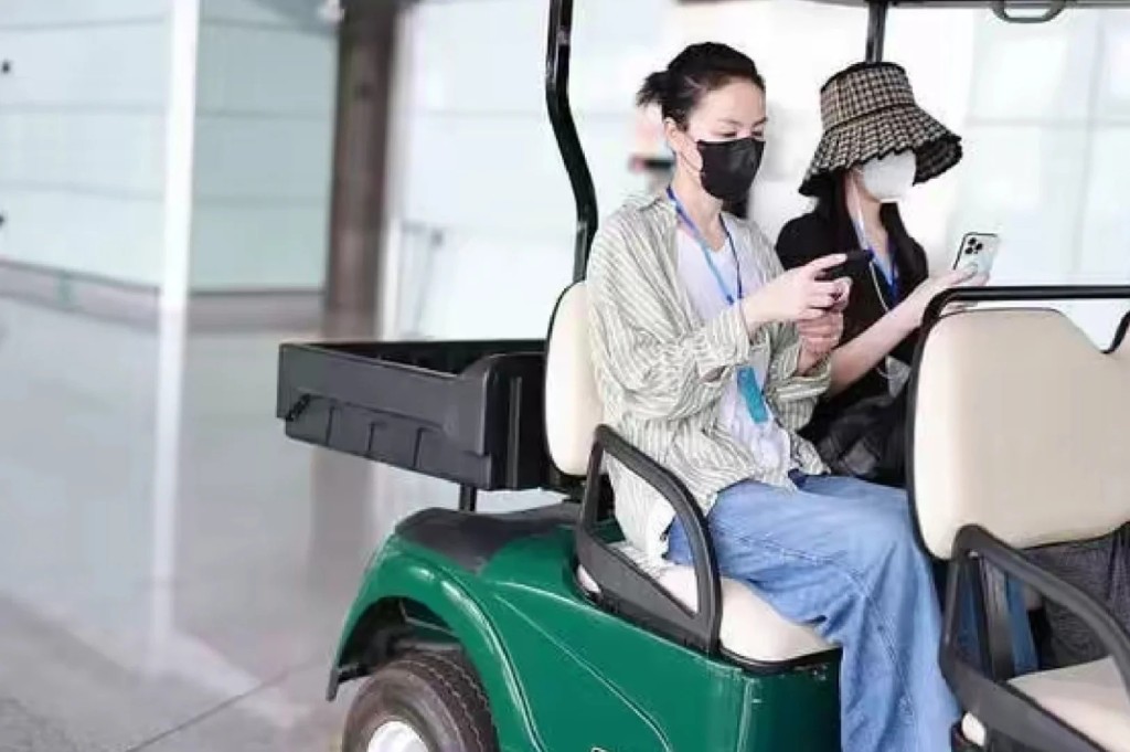 王菲与李嫣登上高尔夫球车时，各自各睇电话。