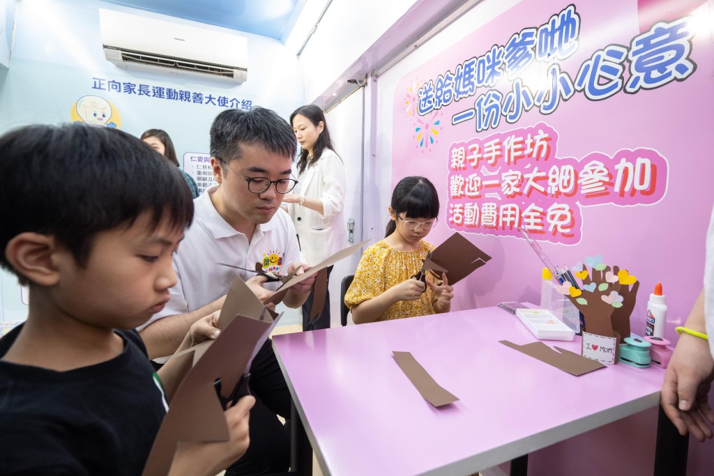 施俊辉（左二）在流动展览车内与公众一同参加亲子手作坊。政府新闻处