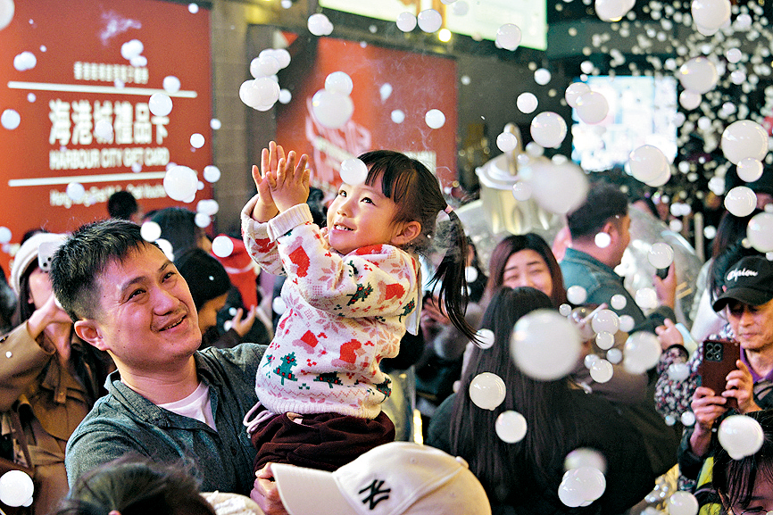 海港城聖誕裝置釋放出飄雪泡泡，小朋友開心得抓拍泡泡。