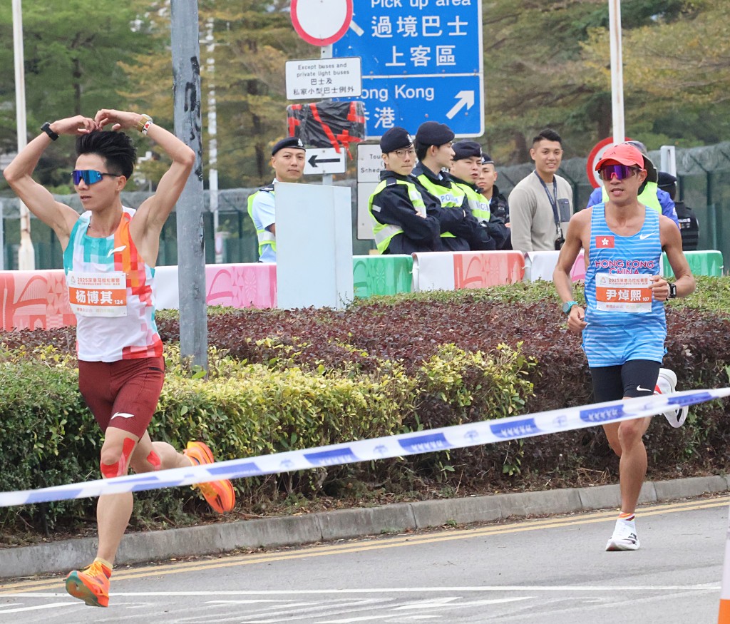 全運會馬拉松測試賽，香港的尹焯熙（後）跟著一位做「心心」手勢給啦啦隊的跑手。 徐嘉華攝