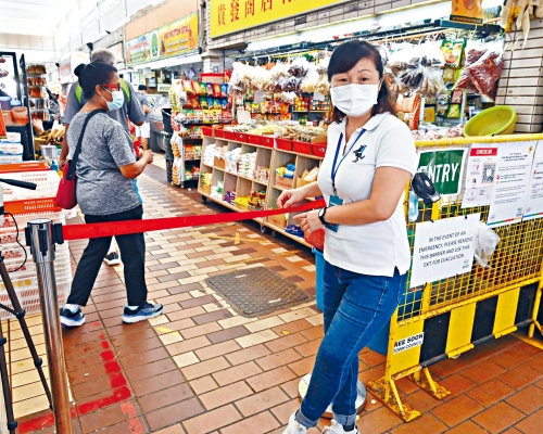 ■新加坡一名工作人員昨天在市場入口控制人流。