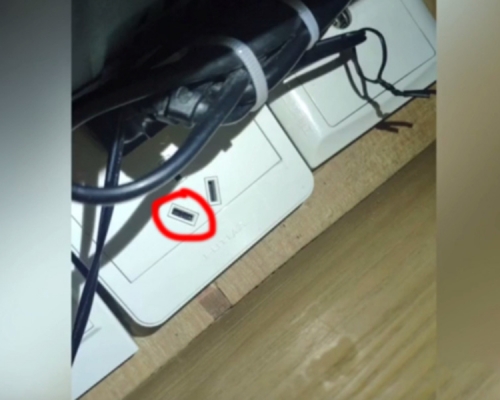正對睡床的電視機下方一個電插座內,發現藏有一枚鏡頭。(網圖)