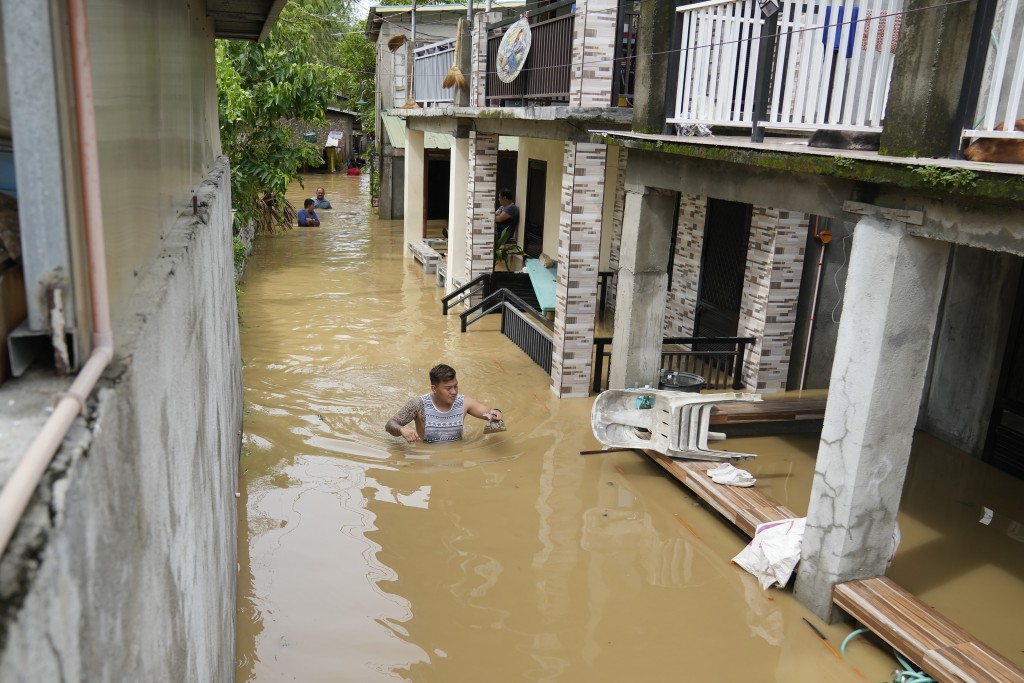 菲律賓布拉幹省聖米格爾鎮的一名居民涉水穿過齊胸深的洪水。AP