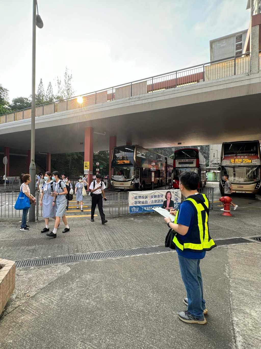 运输署派出约110名人员，实地监察开学日港九新界主要公共运输交汇处、铁路站、学校区、口岸和隧道等交通情况，实时向紧急事故交通协调中心汇报。图示人员（前）在观塘顺利邨学校区监察交通情况。（政府新闻处）