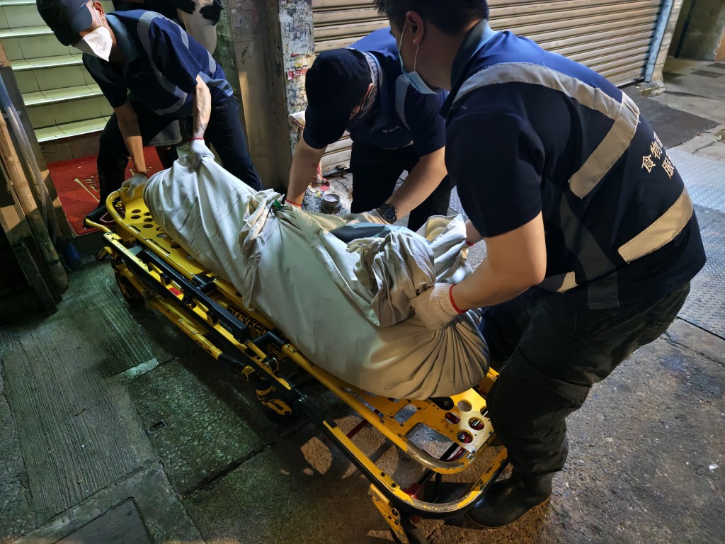 仵工將女死者的遺體搬落樓。