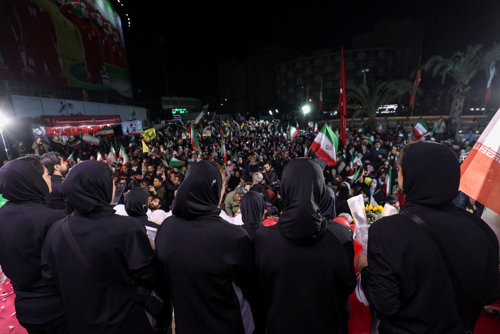 画面中球员身穿国家队球衣并配戴头巾向国旗致敬，受到群众欢迎。路透社