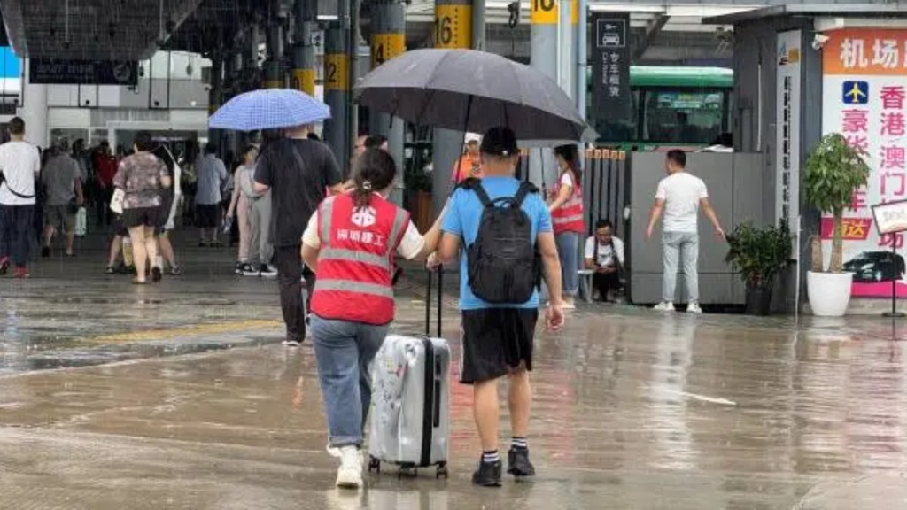 有義工為旅客撐傘。南方+ 有義工為旅客撐傘。南方+