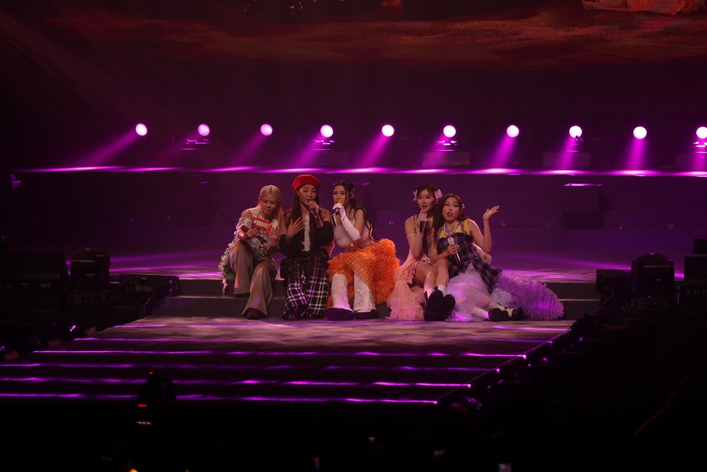 七女合体唱慢歌《Never-never Land》齐齐坐在台边，着超短裙的Candy惊走光不断用手按实裙边。