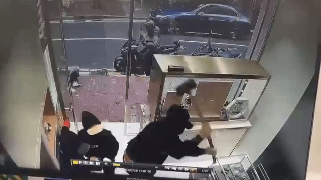 以錘砸向玻璃展示櫃。 以錘砸向玻璃展示櫃。