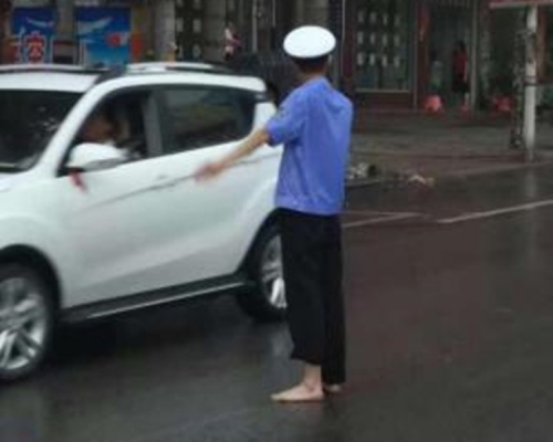 光著腳的交警冒著大雨專注地指揮著來往的車輛。