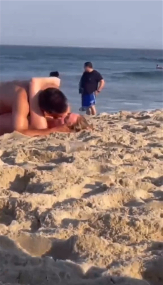 情侣旁若无人地在沙滩上拥吻。