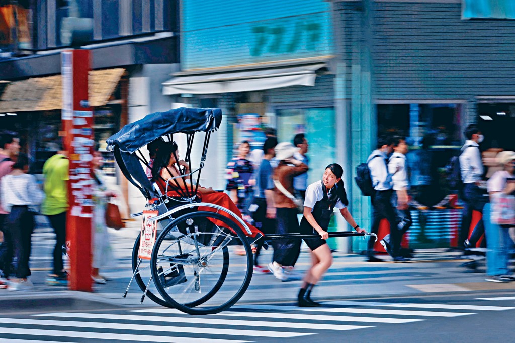女人力车夫在东京浅草街头，拉着客人观光。