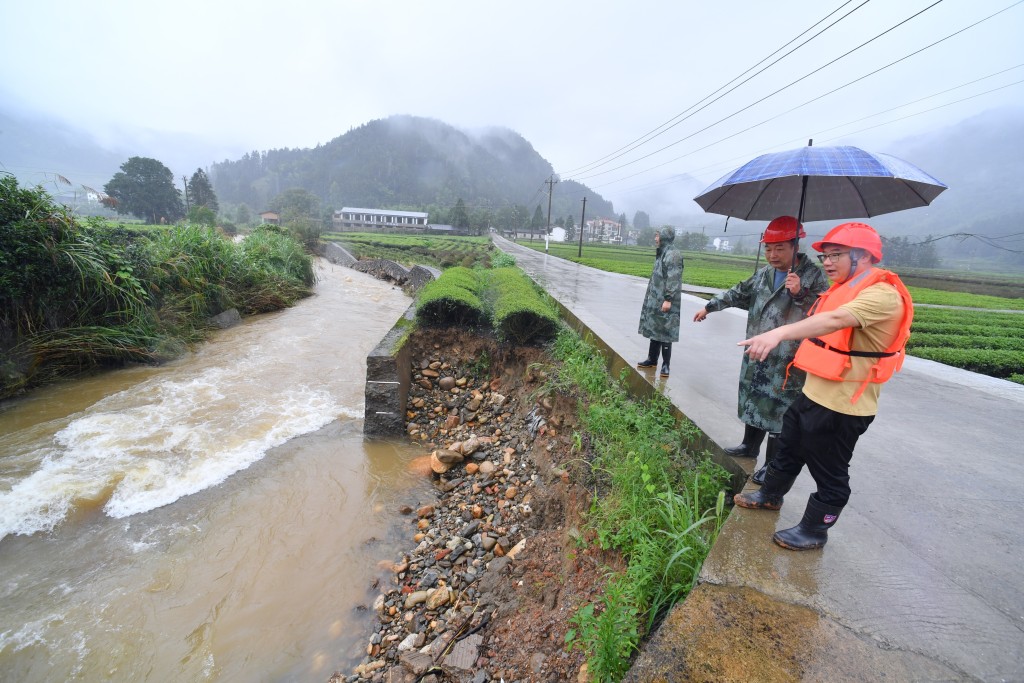 6月16日，福建南平武夷山市星村鎮紅星村防汛人員在查看溪邊一處被洪水沖毀的茶園。 新華社