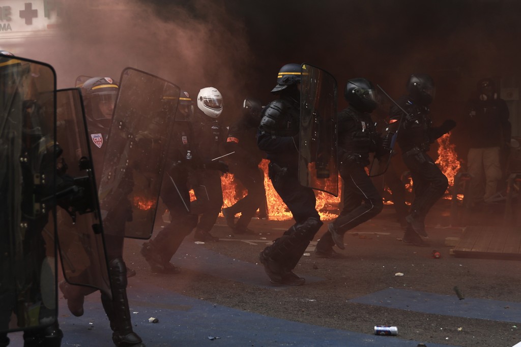 在巴黎举行的示威活动中，防暴警察跑过建筑物前的火堆。AP