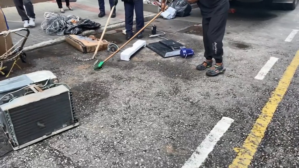 警員及一名非華裔男子用掃帚及木棍壓住蛇身限制其行動，阻止牠爬渠離開。網上片段截圖