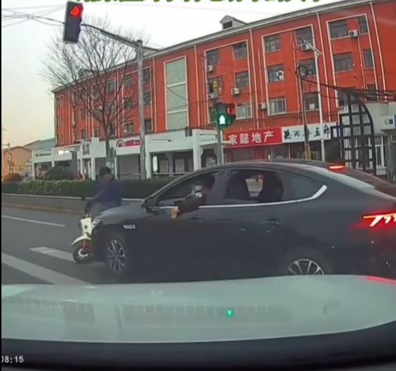 黑色车司机不满女事主停车让路人，举中指挑衅，却撞到一名骑电动车的大叔。
