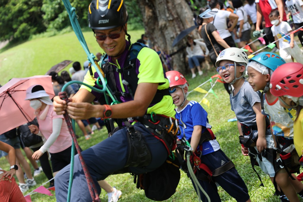 小朋友在教练的悉心指导下学习攀树的入门技巧。