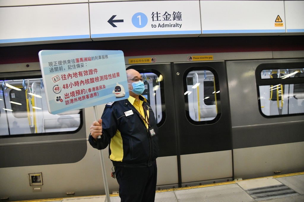 在落馬洲站，有港鐵職員舉牌提醒市民過關所需文件。（盧江球攝）