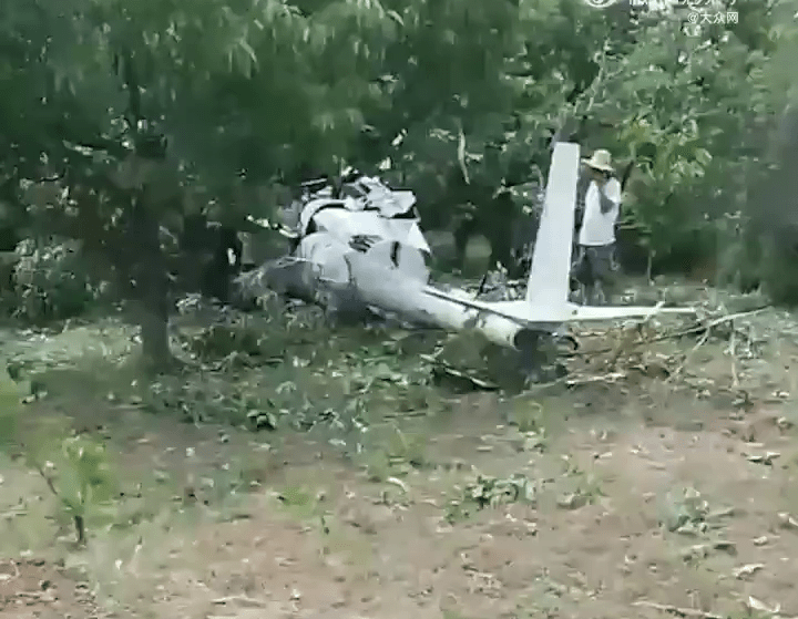 曝光的现场画面显示，在一处小树林里，一架白色的小型直升飞机的机身坠毁在树林里。
