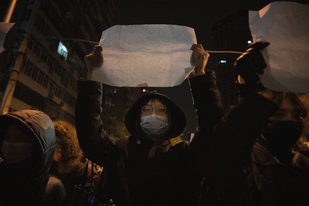 一名示威者舉著一張白紙並高喊口號，示威者對嚴格的防病毒措施感到憤怒。AP